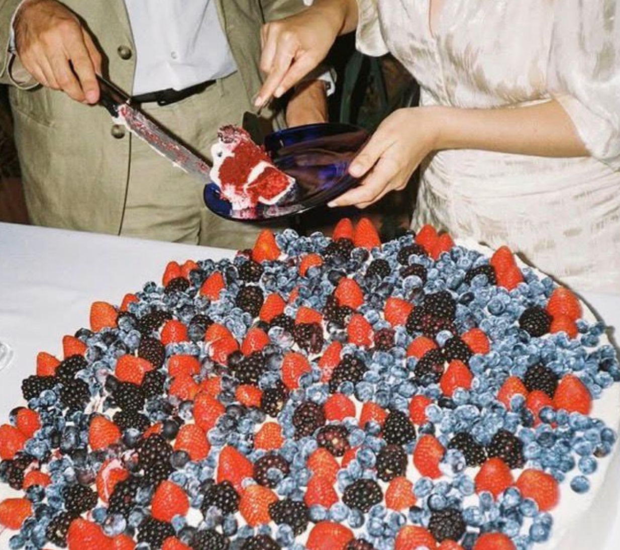 Una parella tallant un gran pastís amb fruits vermells